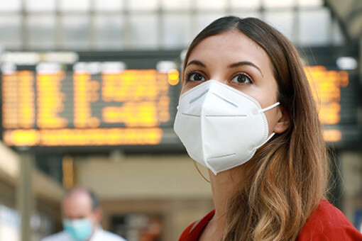 Frau mit Maske auf Bahnhof