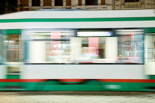 Eine grün-weiße Straßenbahn der Magdeburger Verkehrsbetriebe fährt an uns vorüber. Mit einer gewissen unschärfe wird ihre Schnelligkeit gezeigt.