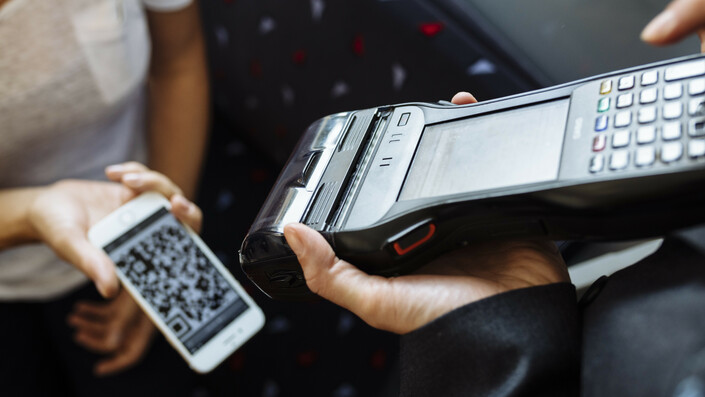Tarife Fahrkarten A train attendant's mobile ticket reader scans the QR code of a ticket on a smartphone.