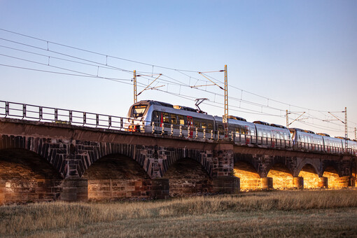 En schwarz-silberner Zug vom Typ Bombardier Talent 2 von Abellio Rail Mitteldeutschland fährt über eine Brücke herauf.