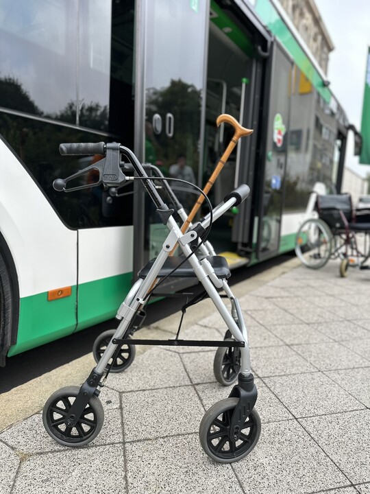 eine Gehhilfe steht an einem grün-weißen Bus